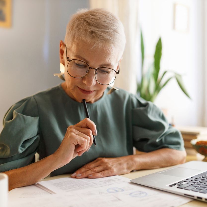 Elderly businesswoman in glasses examining contract of agreement
