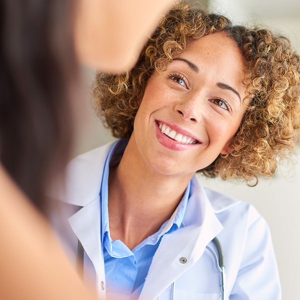 Smiling physician listening to her patient