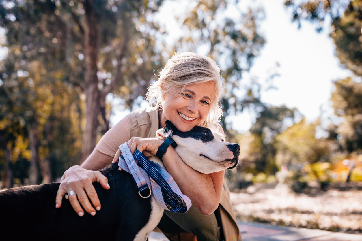 woman embracing pet dog in nature